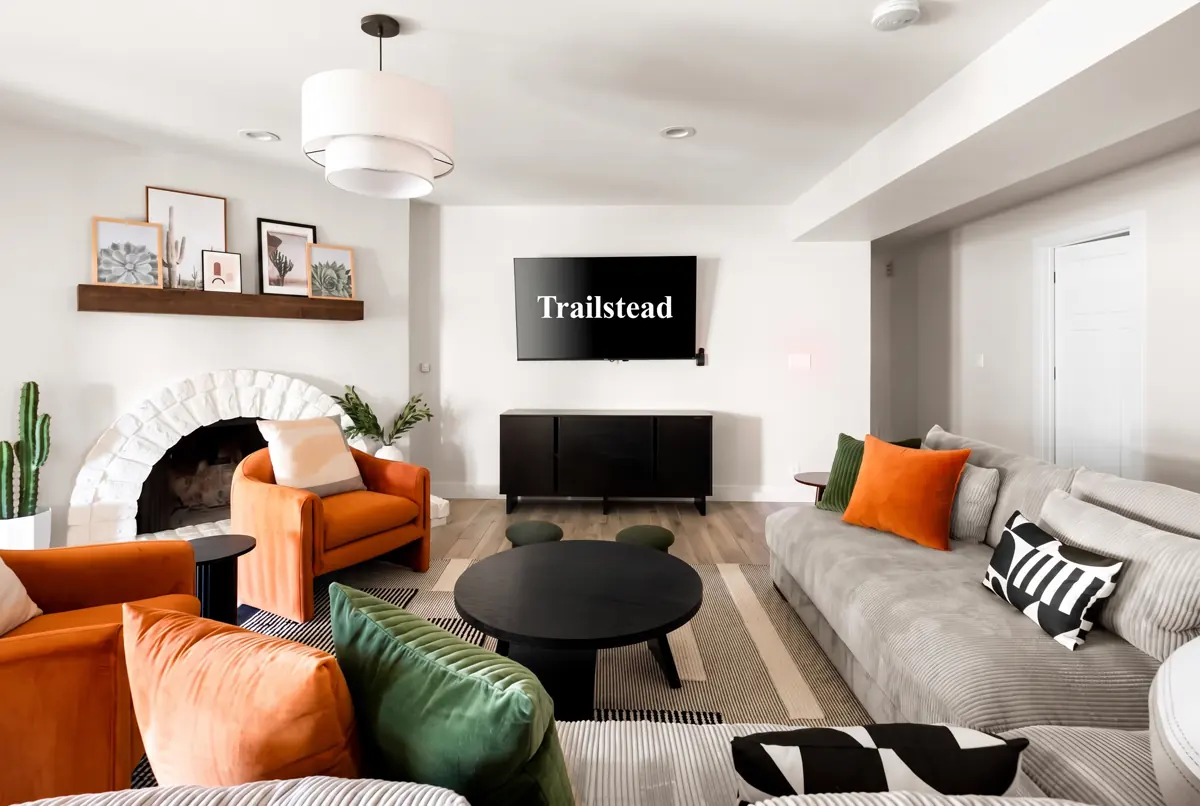 The Sunkiss — living room featuring a sectional sofa, orange accent chairs, coffee table, and arched fireplace